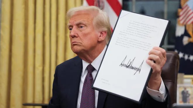 Photo of Donald Trump holding an executive order signed by him in his hands